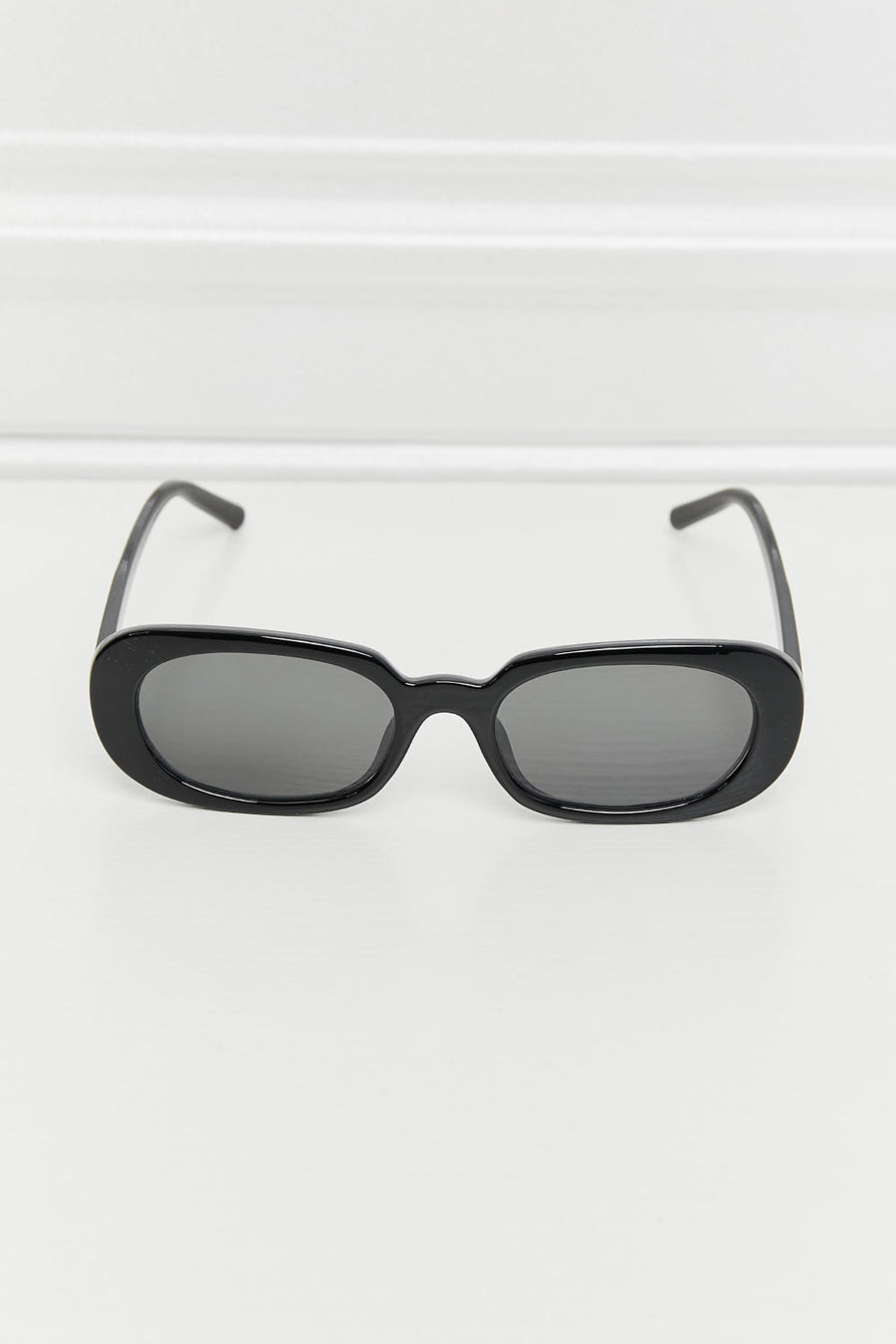 Black oval sunglasses with dark lenses and a sleek frame.