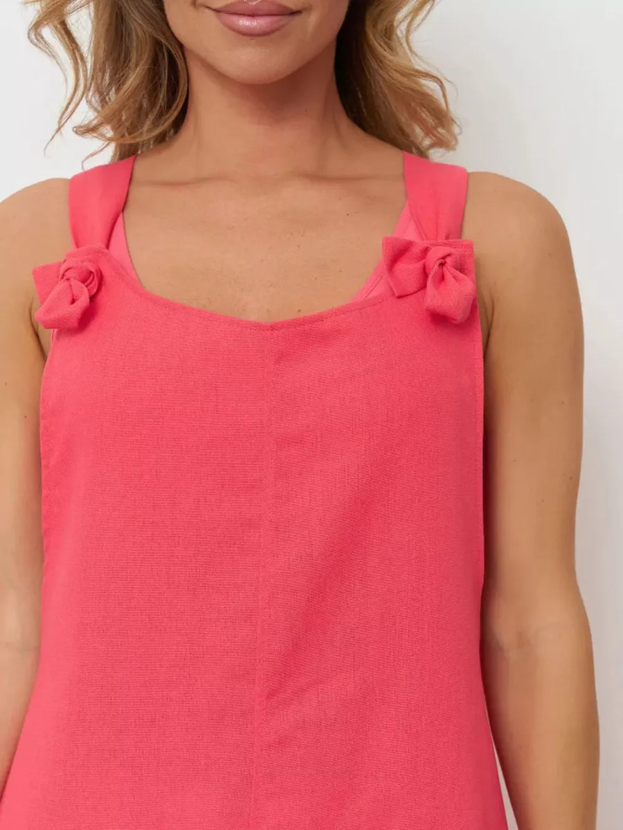 Cotton tie-strap romper in coral pink with V-neck and bow details on straps.