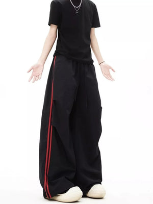 Black wide-leg sweatpants with red side stripes and adjustable drawstring waist.
