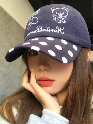 Navy baseball cap with white polka dots and embroidered bear graphic.