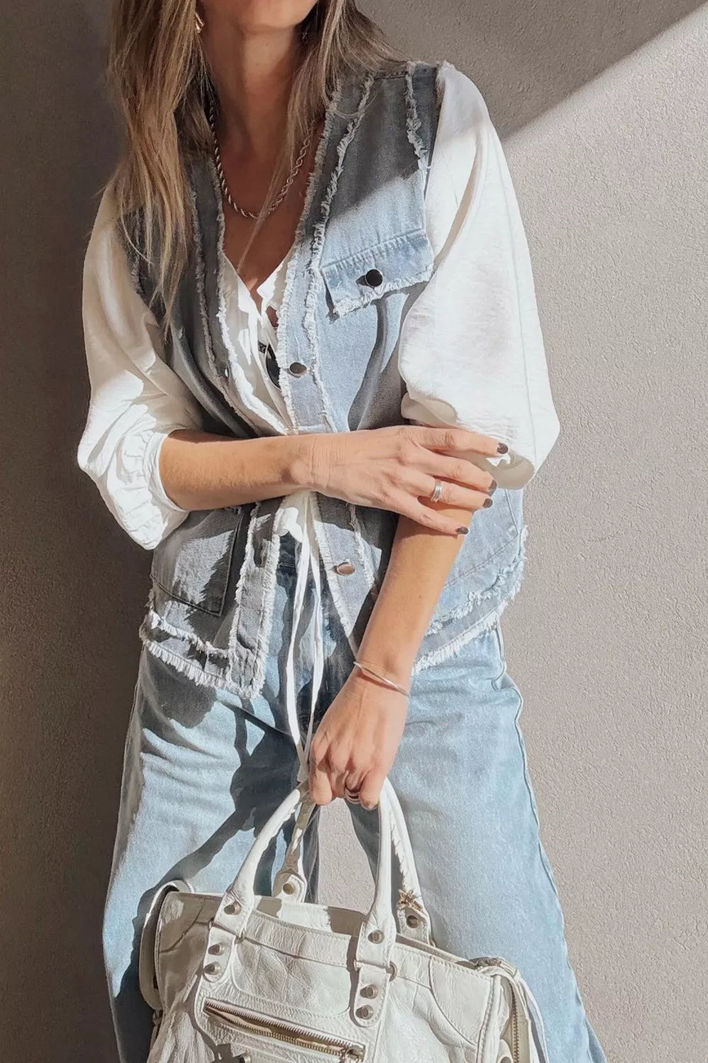 Light wash denim vest with frayed edges, button-down front, and chest pockets.