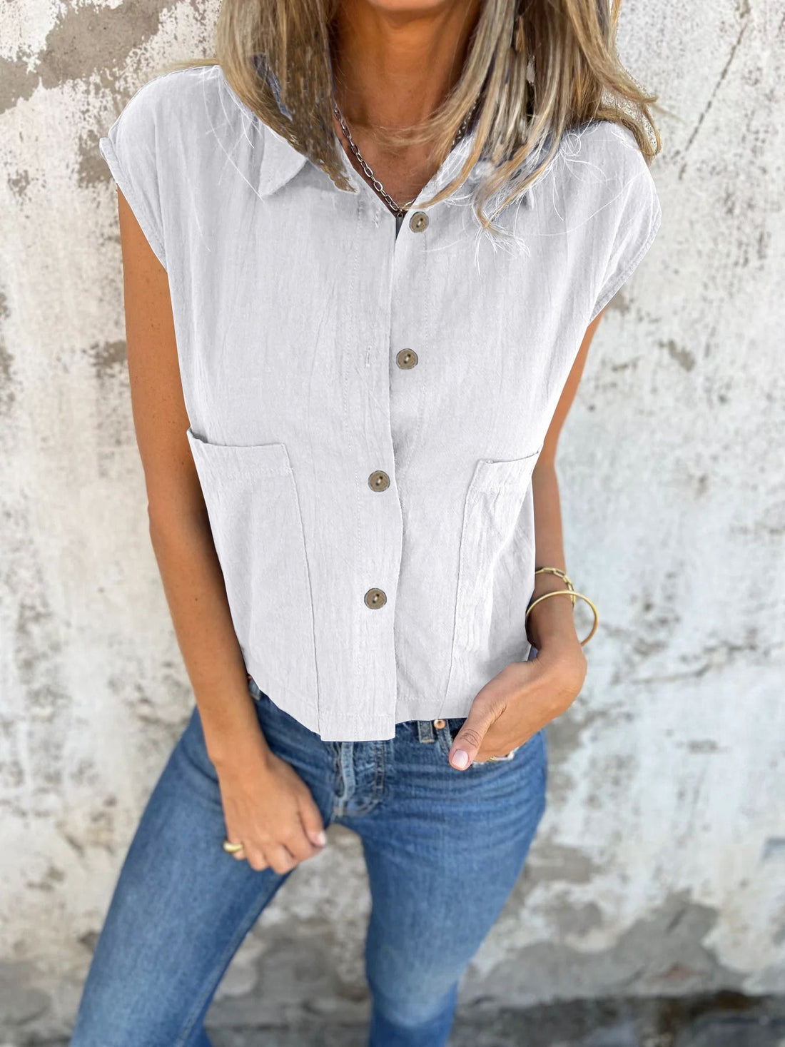 White button-down cap sleeve shirt with two chest pockets and a cropped fit.