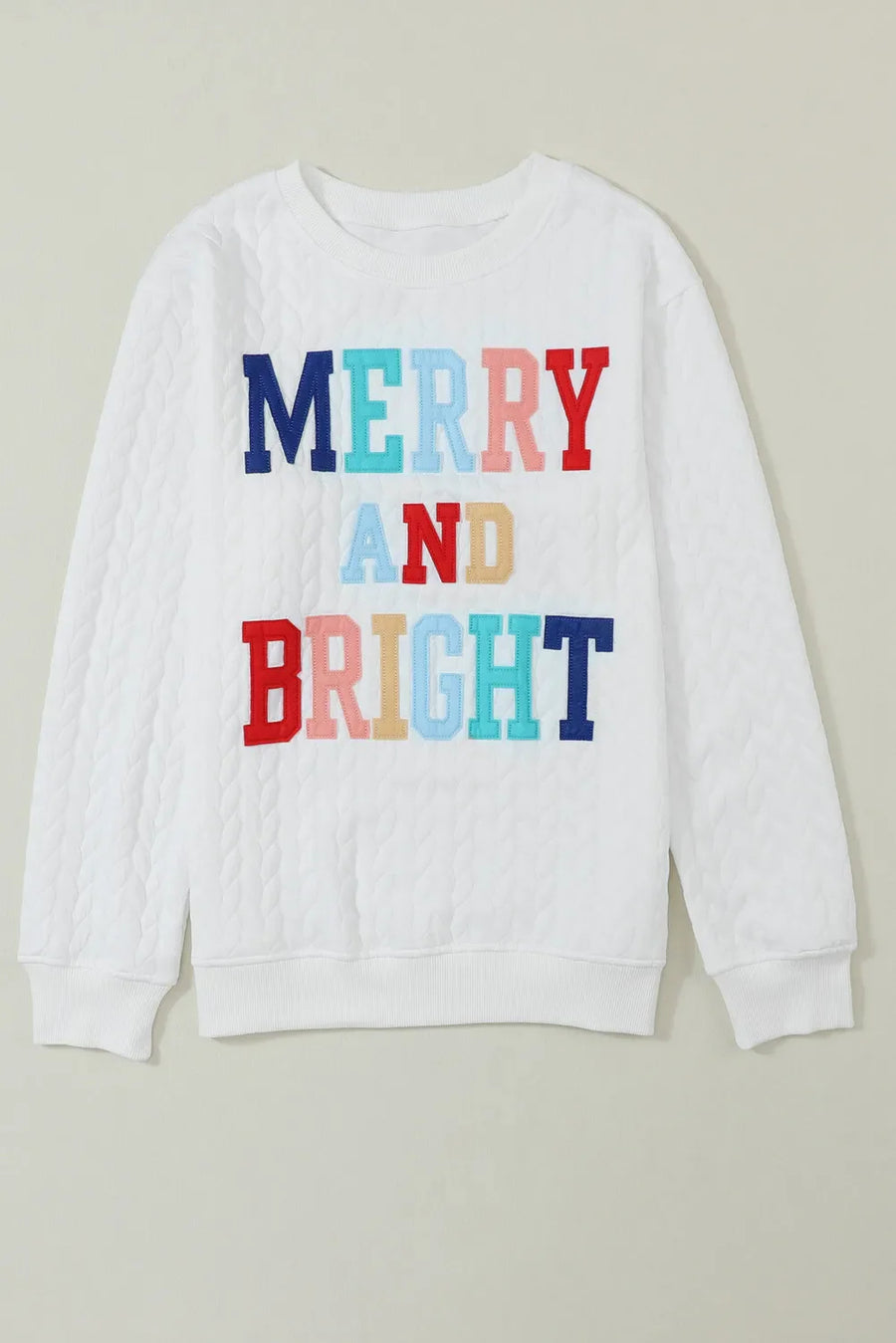 White quilted sweatshirt with colorful "Merry and Bright" applique text.