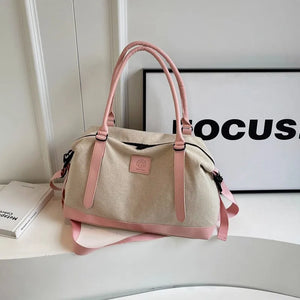 Canvas weekend holdall duffel bag in beige with blush pink accents and straps.