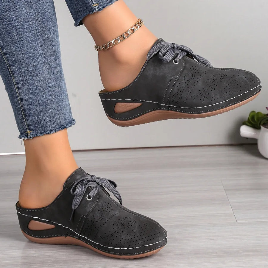 Perforated lace-up mule flats in dark gray with white stitching and cutout sides.
