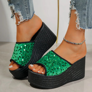 Green sequin platform wedge slides with black soles and frayed jeans.