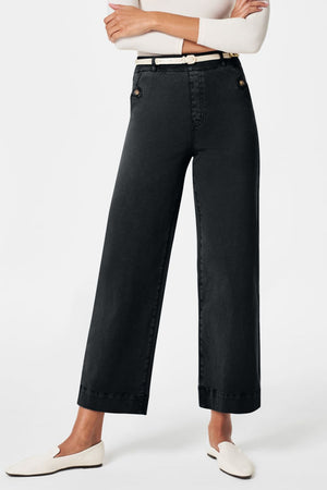 Wide-leg dark gray denim trousers with button details and a white belt.