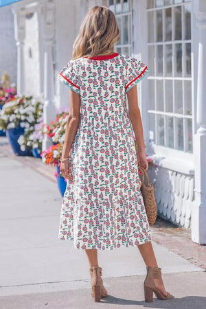 Vibrant floral tiered midi dress with red and blue trim, flutter sleeves, and a round neckline.