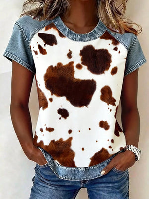 Contemporary denim patchwork blouse with cow print front and short sleeves.