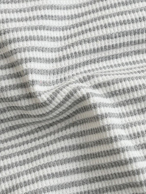 Baby one-piece with grey and white horizontal stripes in waffle knit fabric.
