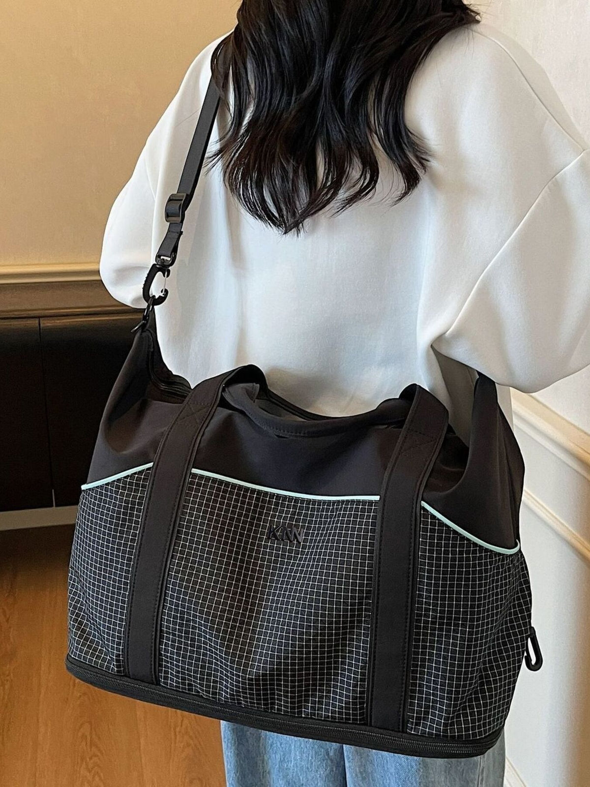 Black nylon duffel bag with grid pattern and light blue trim, detachable strap.