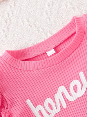 Pink ribbed cotton blend baby dress with "honey" graphic and bubble texture detail.