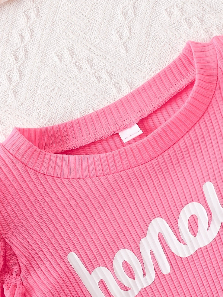 Pink ribbed cotton blend baby dress with "honey" graphic and bubble texture detail.