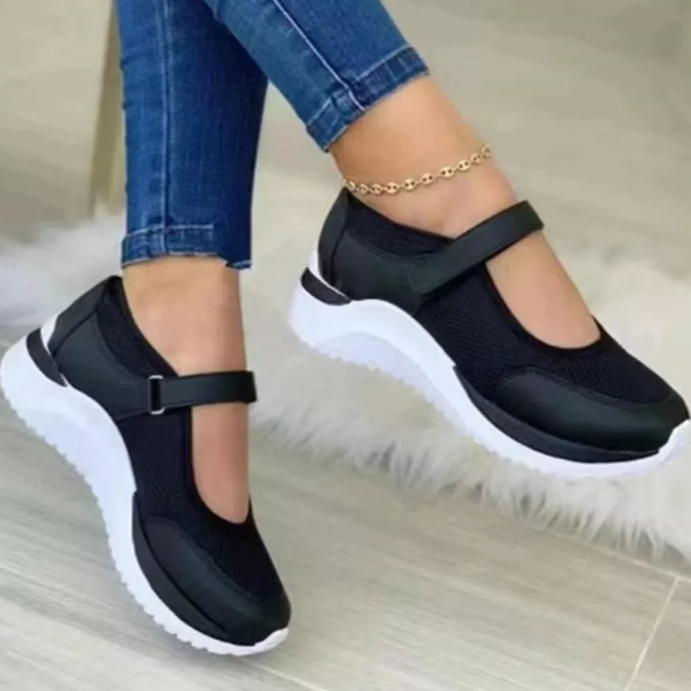Black mesh round toe Mary Janes with adjustable strap and chunky white sole.