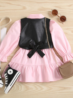 Toddler pink cotton dress with black faux leather vest, bow detail, and ruffled sleeves.
