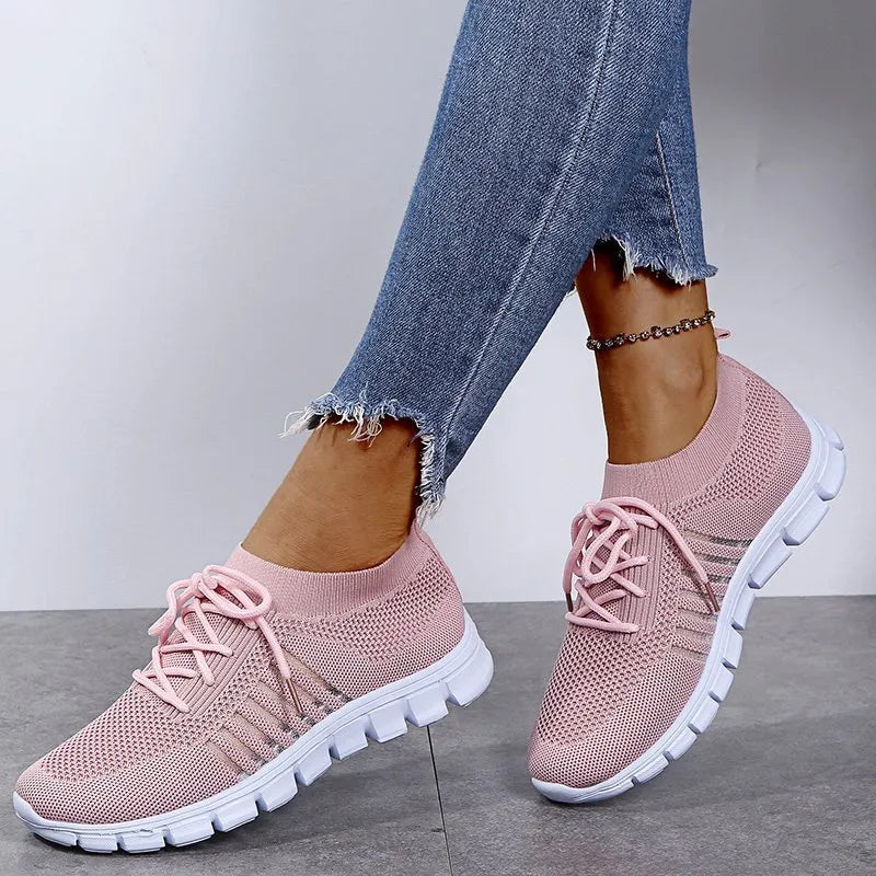 Pink knit runner sneakers with ribbed lace-up detail and white soles.