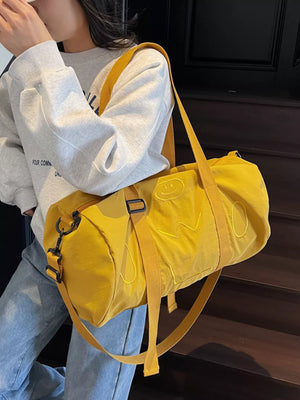 Yellow duffel bag with embroidered smiley face and adjustable strap