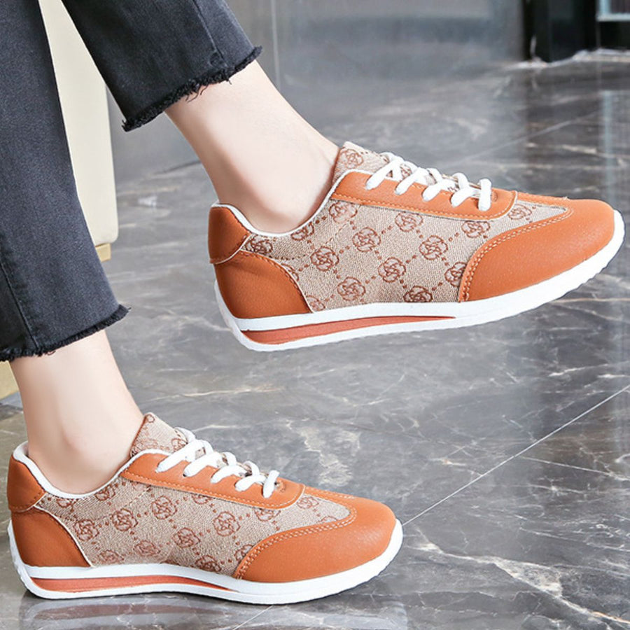 Lace-up round toe sneakers in tan with brown logo pattern and orange accents.