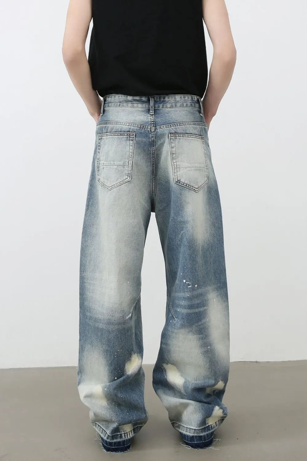 Distressed painterly wide-leg jeans in medium wash denim with paint splatters and a faded look.