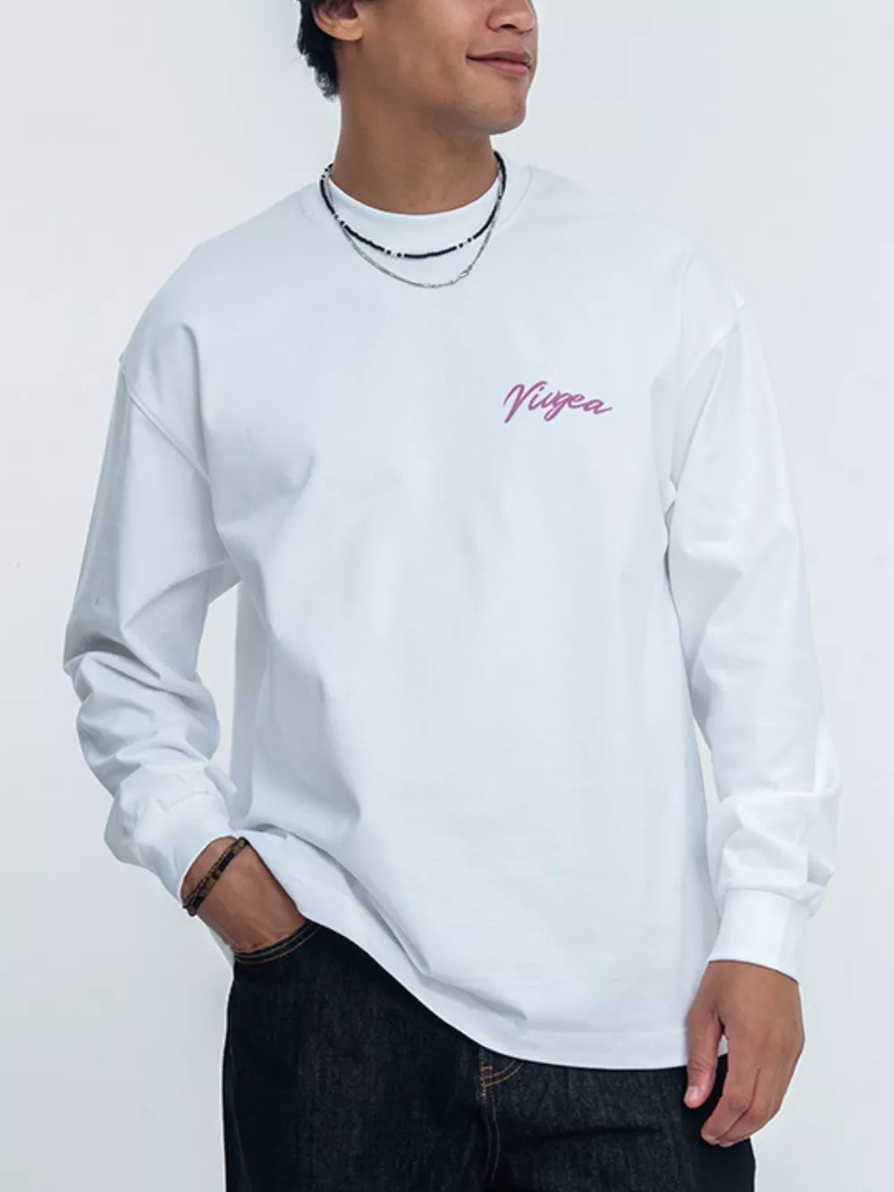 White long sleeve t-shirt with pink script logo on chest.