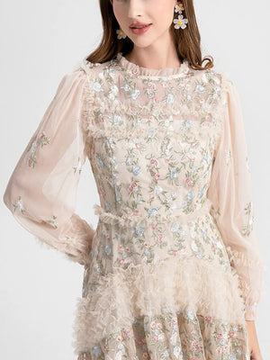 Embroidered floral tulle maxi gown with ruffled neckline and sleeves.