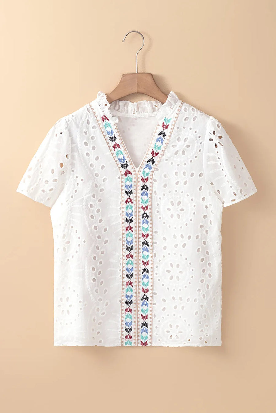 White eyelet V-neck blouse with colorful embroidered trim and ruffled collar.