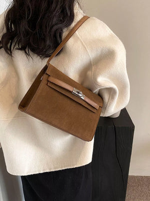 Elegant buckle shoulder bag in coffee color suede with a silver clasp and tan leather trim.