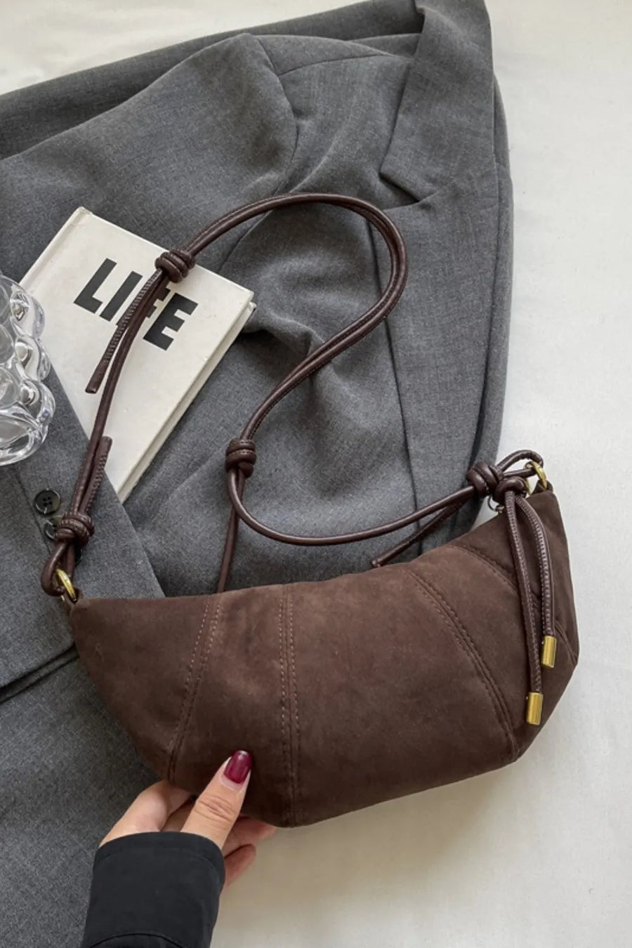 Brown suede crescent shoulder bag with knot detail and gold hardware