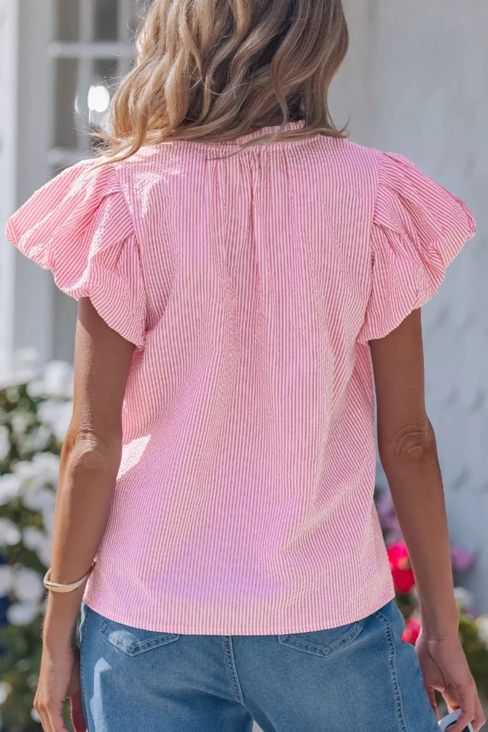 Pink striped short sleeve blouse with textured seersucker fabric and flutter sleeves.