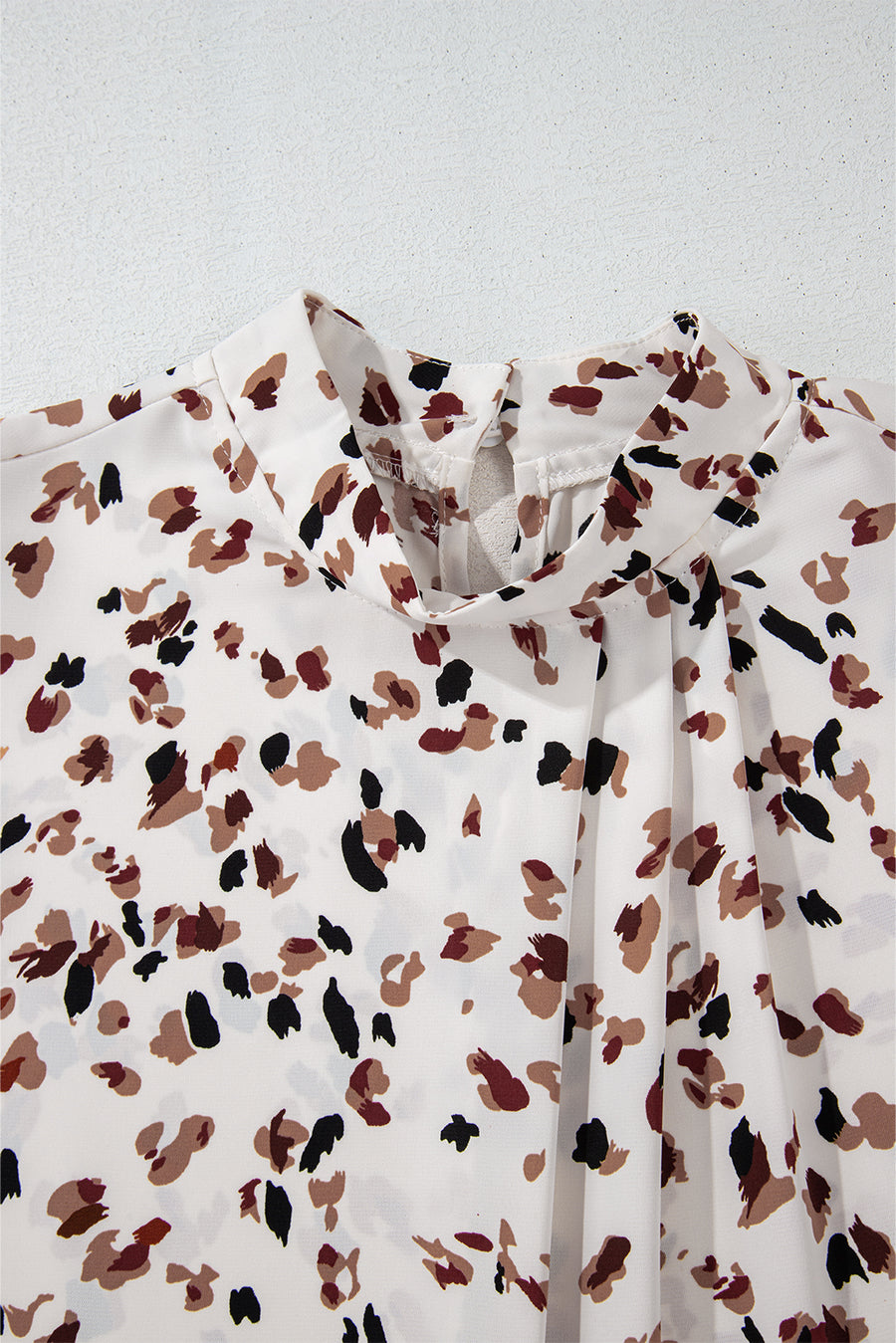 White high-neck blouse with abstract print and pleat detail