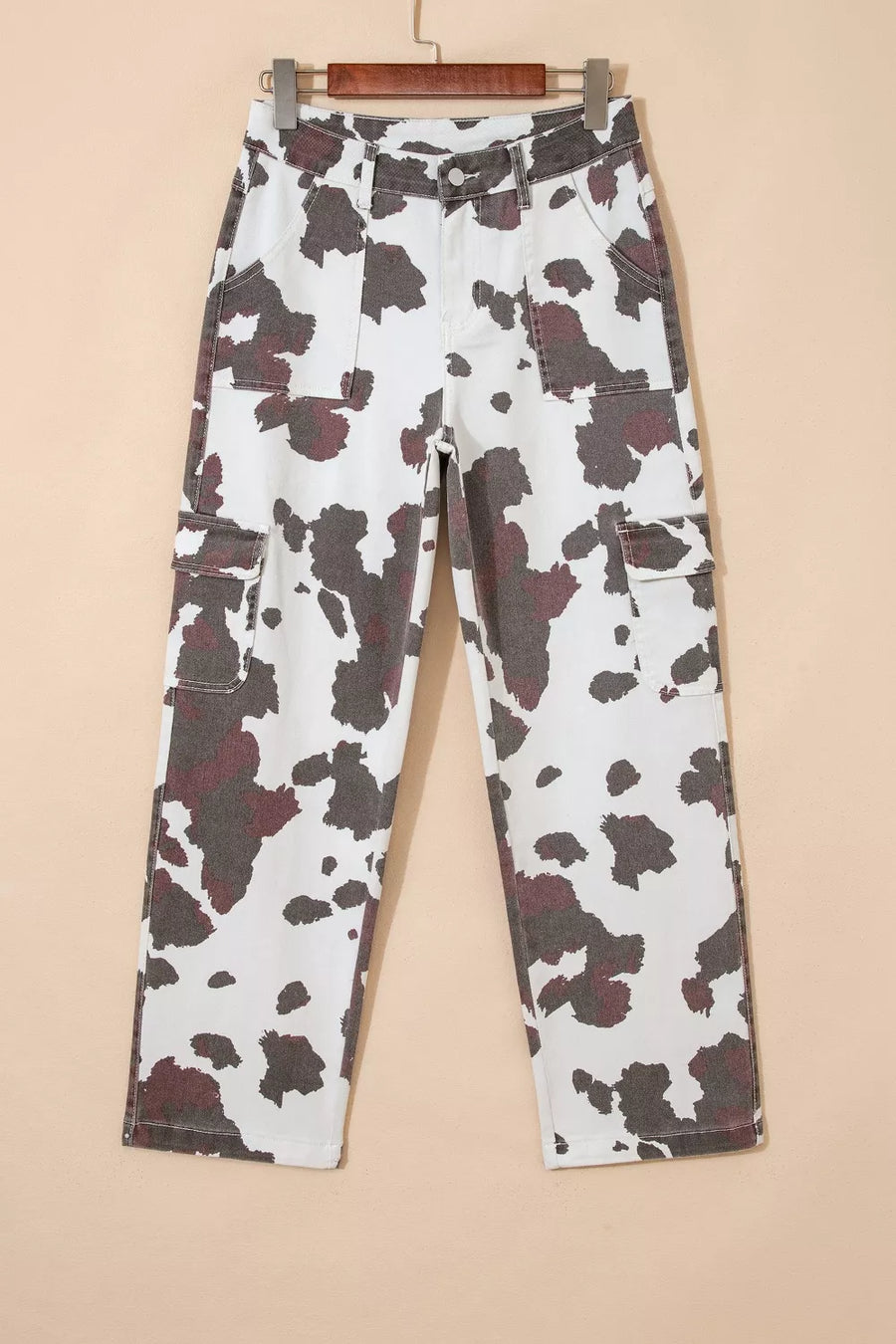 Cow print utility jeans with cargo pockets in a white and brown pattern.
