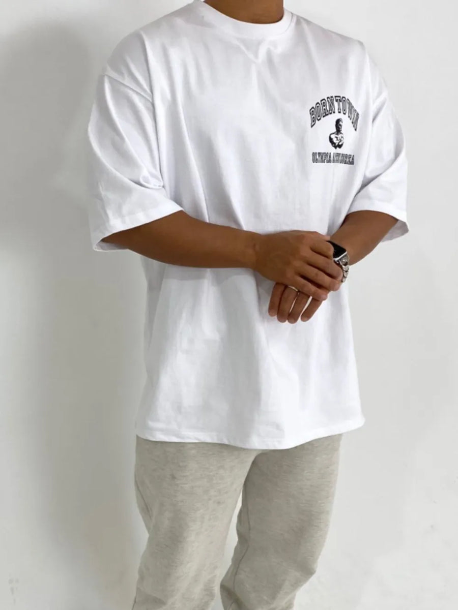 White oversized t-shirt with "BORN TO WIN OLYMPIA KOREA" graphic print on chest.