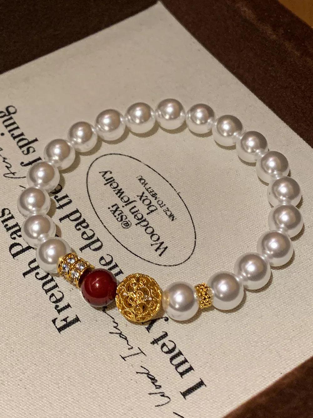 Elegant pearl beaded bracelet with gold accents and a red bead.