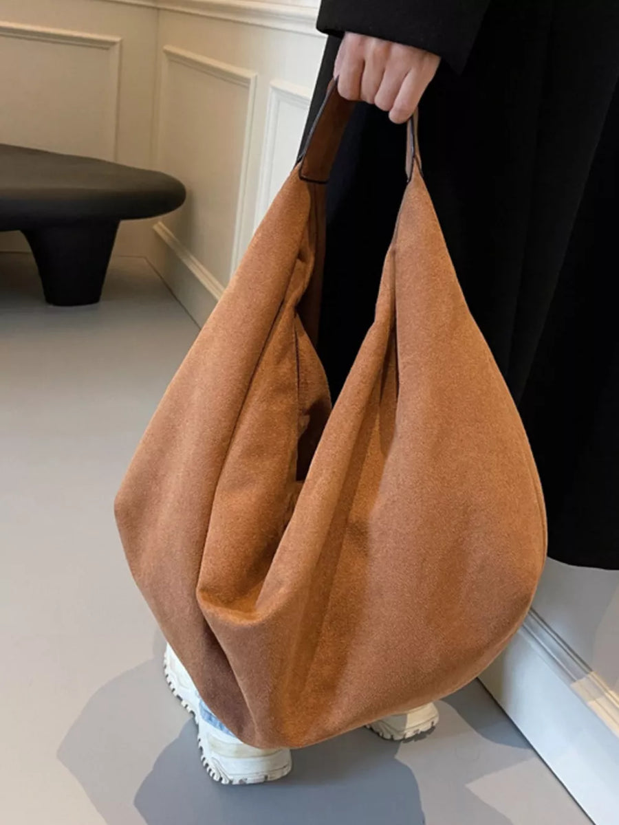 Spacious yellow brown suede shoulder bag with a slouchy silhouette and zipper pocket detail.