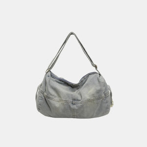 Washed denim hobo bag in light blue with adjustable strap and zippered top.