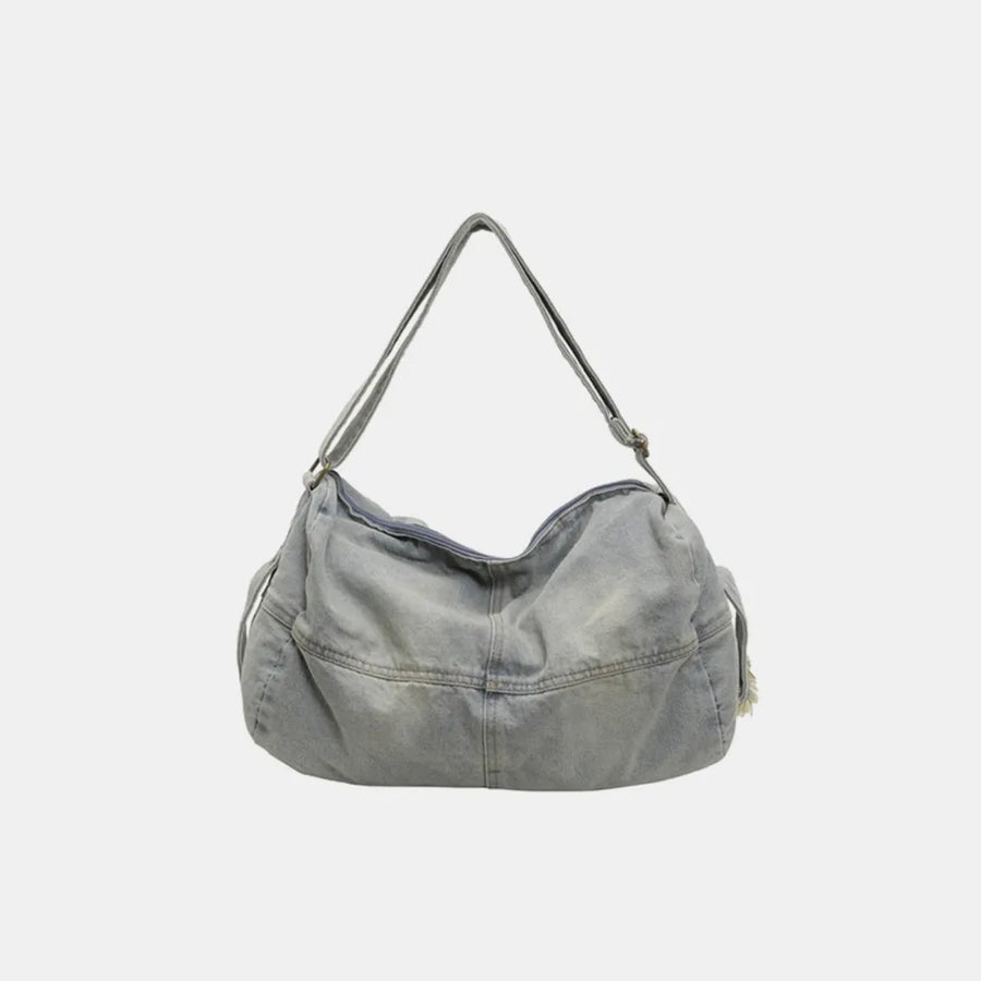 Washed denim hobo bag in light blue with adjustable strap and zippered top.