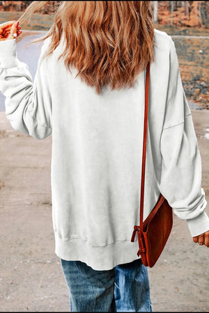 White cotton sweatshirt with slit hem detail, worn with jeans and a crossbody bag.