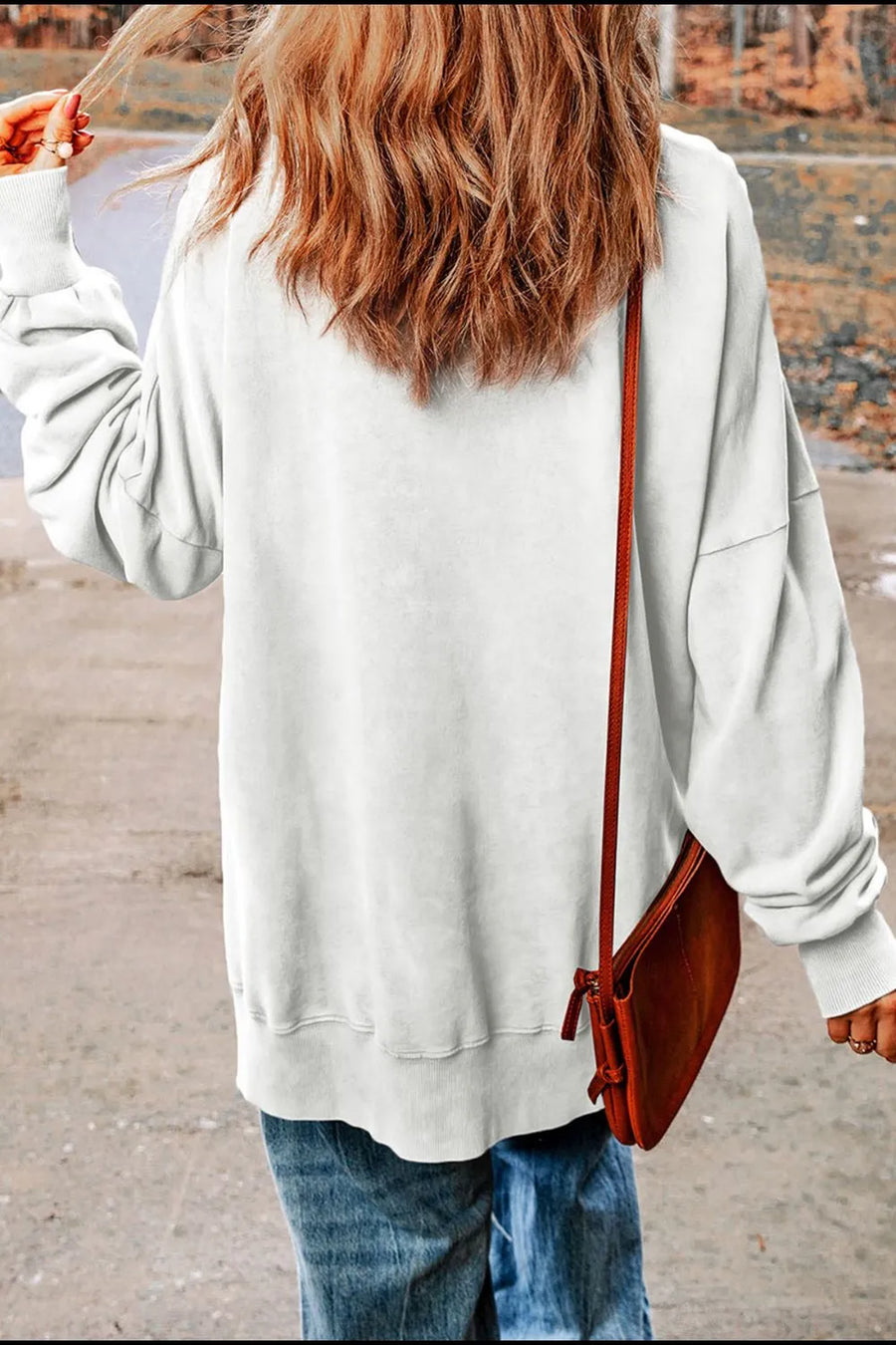 White cotton sweatshirt with slit hem detail, worn with jeans and a crossbody bag.