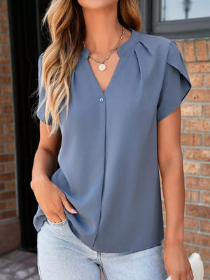 Blue V-neck blouse with petal sleeves and a single button closure, styled with a gold necklace.