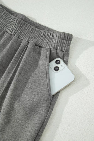 Dark gray wide-leg pants with elastic waistband and side pocket holding a phone.