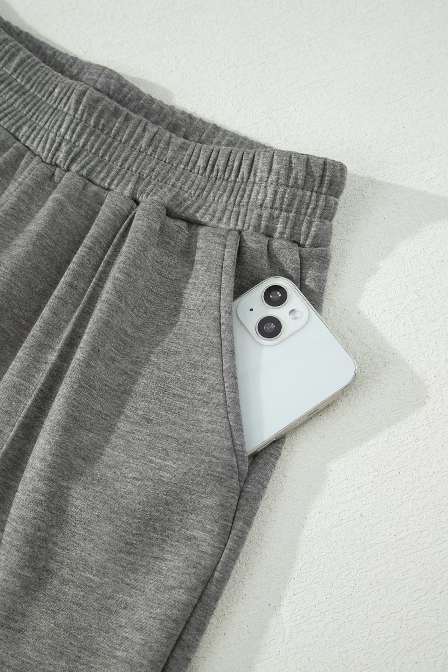 Dark gray wide-leg pants with elastic waistband and side pocket holding a phone.