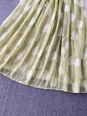 Green chiffon maxi dress with white floral embroidery and a belted waist.