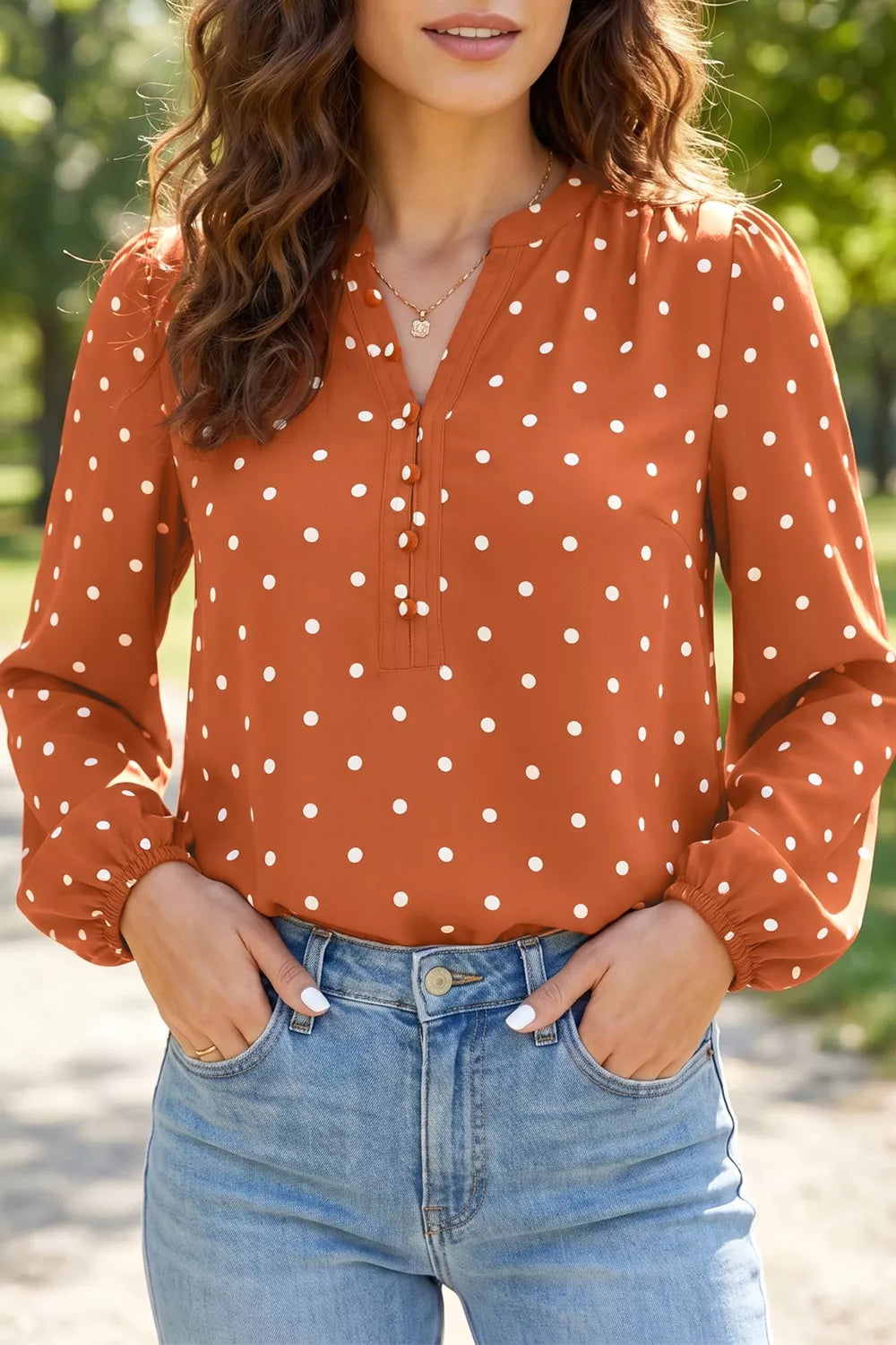 Charming polka dot V-neck shirt with decorative buttons and long sleeves.