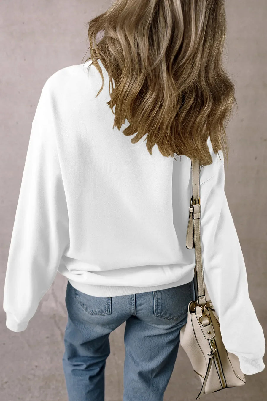 White crewneck sweatshirt with long sleeves and a relaxed fit, styled with jeans.