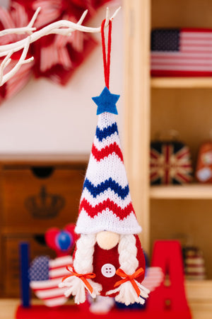 Patriotic knit gnome ornament with red, white, and blue chevron hat and white braids.