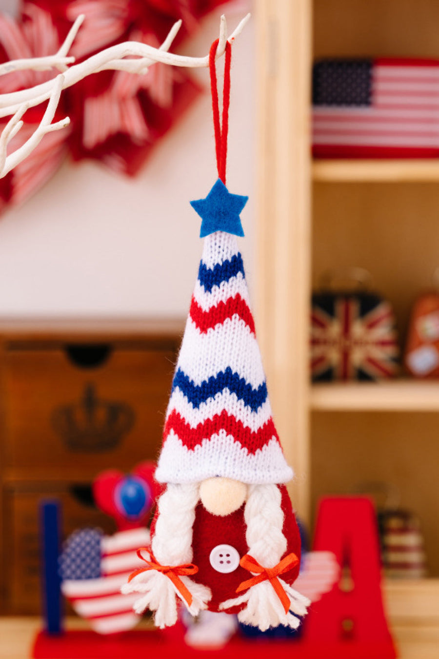 Patriotic knit gnome ornament with red, white, and blue chevron hat and white braids.