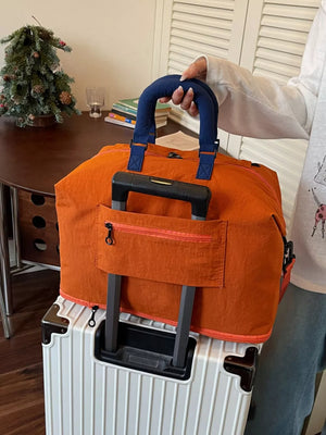 Orange Oxford cloth travel bag with blue handles and orange trim, featuring a luggage sleeve.
