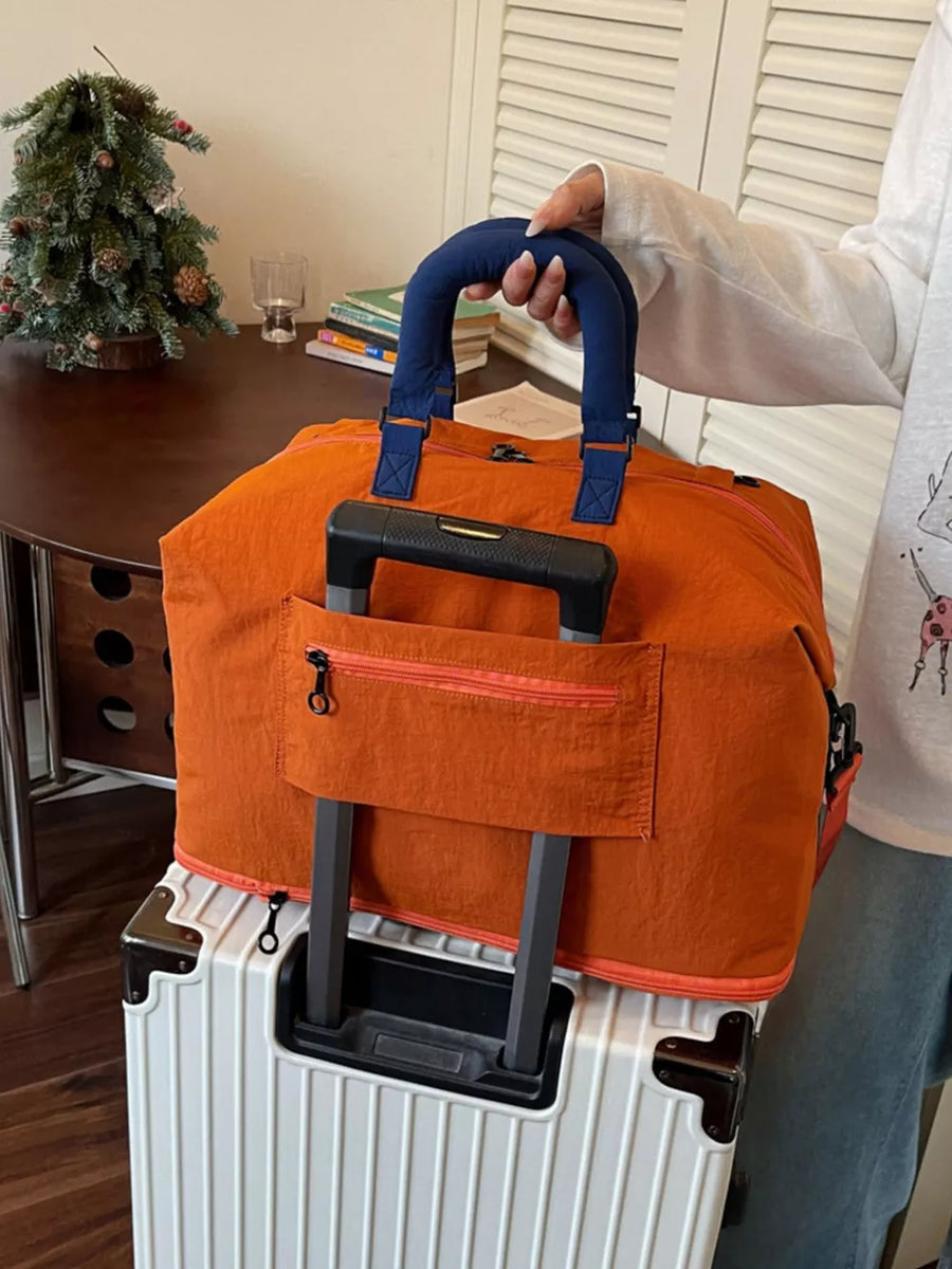 Orange Oxford cloth travel bag with blue handles and orange trim, featuring a luggage sleeve.
