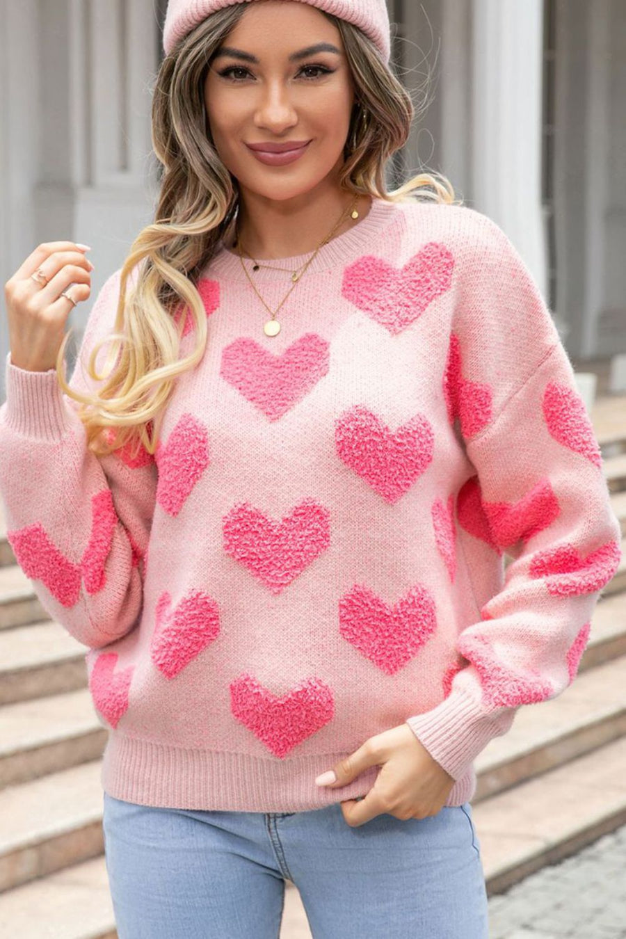 Blush pink knit sweater with textured heart pattern, crew neck, and long sleeves.