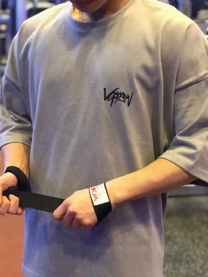 Gray oversized graphic tee with crew neck and short sleeves, featuring a black logo.